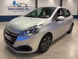 Une voiture argentée est garée dans un showroom où l'on aperçoit un logo sur le mur.