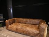 un canapé en cuir marron posé sur un parquet en bois massif
