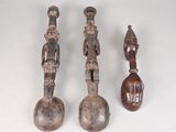 trois figurines en bois de formes et de tailles différentes posées sur une surface blanche