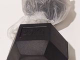 a black object sitting on a white surface next to a plastic bag