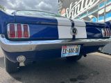 une photo d'une Mustang bleue et blanche garée devant un magasin