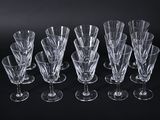 six clear wine glasses are lined up on a black surface