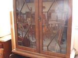 a wooden cabinet with a glass door and a desk