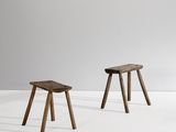 two small wooden stools sitting on top of a white surface