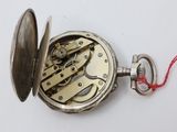 a silver pocket watch with a red string around it