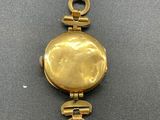 a close up of a gold bracelet with a coin on it