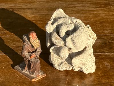 une petite statue représentant un homme assis près d'un rocher