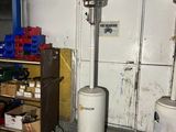 trois chauffages à gaz dans un garage où se trouve un chariot rempli de cartons