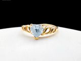 a close up of a gold ring with a heart shaped blue topaz