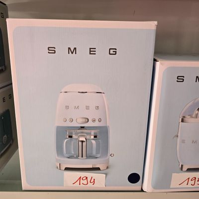 deux cartons contenant des machines à café Smeg sur une étagère dans un magasin