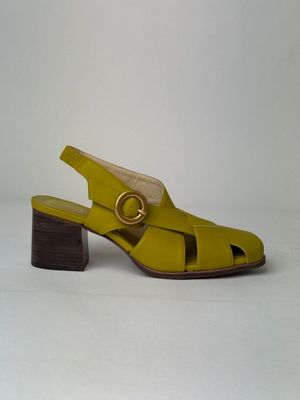 un gros plan sur une paire de sandales jaunes posées sur une surface blanche