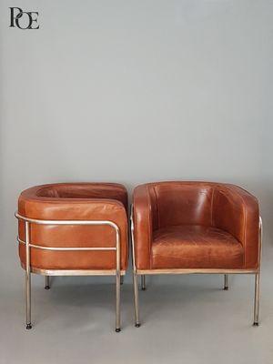 deux fauteuils en cuir marron placés l'un à côté de l'autre sur un sol blanc