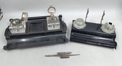 trois objets en argent posés sur une table, à côté d'un stylo et d'un crayon