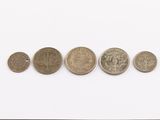 five different coins are arranged in a row on a white surface