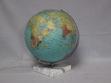 un globe bleu et vert posé sur un socle blanc