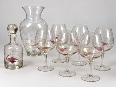 Plusieurs verres à vin et une carafe sont alignés sur une table