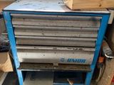 une armoire à outils bleue posée dans un garage, à côté d'un tas de bois
