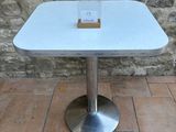 a white table with a glass on it on a brick floor