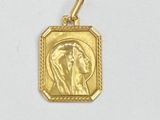 un gros plan sur un pendentif en or représentant une femme de profil