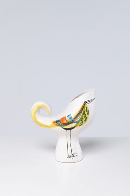 small ceramic bird with yellow beak sitting on a white vase