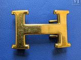 gold letter h on a blue leather surface with a black background