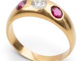 a close up of a gold ring with a diamond and ruby stones
