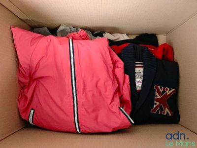 une boîte remplie de vêtements, avec un oreiller à l'intérieur