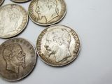 several old silver coins sitting on top of each other on a white surface