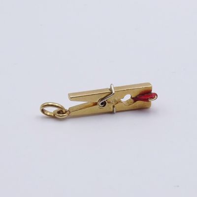 un gros plan sur une petite barrette dorée ornée d'une perle rouge