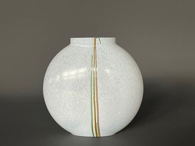 un vase blanc posé sur une table ornée d'une bande verte