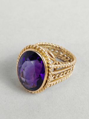 gros plan d'une bague en or avec une pierre violette