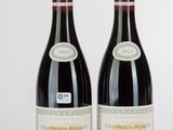 two bottles of red wine sitting next to each other on a table