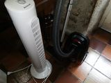 a white air conditioner sitting next to a black and white vacuum