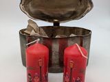 two red candles sitting next to a silver container on a white surface