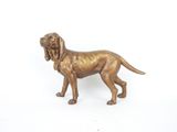 statue en bronze représentant un chien posée sur une surface blanche, avec un fond blanc