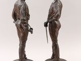 pair of bronze figurines of a man and a woman holding golf clubs