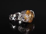 un gros plan d'une bague sertie d'un diamant jaune et blanc posée sur une surface noire