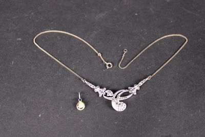 une photo d'un ensemble composé d'un collier et de boucles d'oreilles posé sur un fond noir