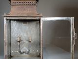 a small metal lantern sitting on a table with a glass door open