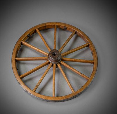 a wooden wagon wheel with a metal spoke on a wall