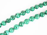un gros plan sur un collier de perles de marbre vert posé sur une surface blanche