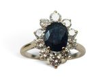 gros plan d'une bague avec une pierre bleue entourée de diamants blancs
