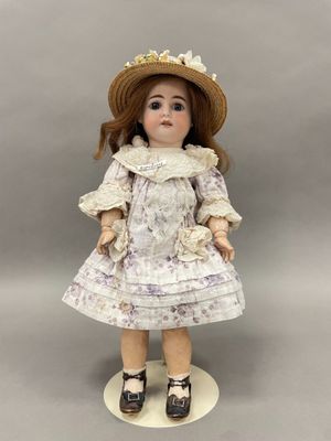 une poupée en porcelaine représentant une petite fille portant un chapeau et une robe