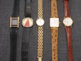 Quatre modèles de montres différents sont alignés sur une surface noire