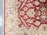 an old red and beige rug with a floral design on it
