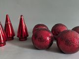 several red christmas balls and cones on a white surface