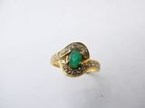 an emerald and diamond ring on a white surface
