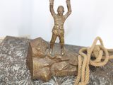 a bronze statue of a man on a rock with a rope