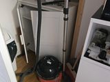 un aspirateur posé par terre à côté d'un réfrigérateur