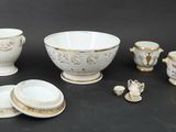 a group of white and gold dishes and cups on a table